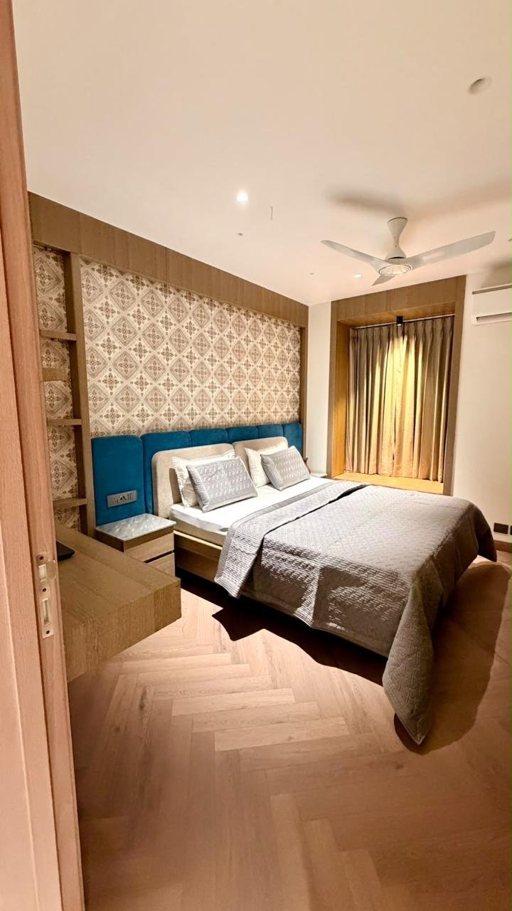 Bedroom with patterned headboard, blue accents and warm lighting