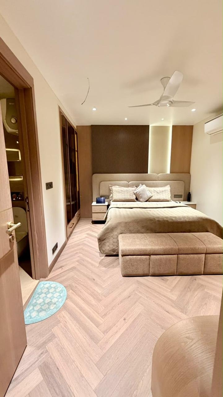Bedroom with herringbone floor, neutral bed and timber wardrobe