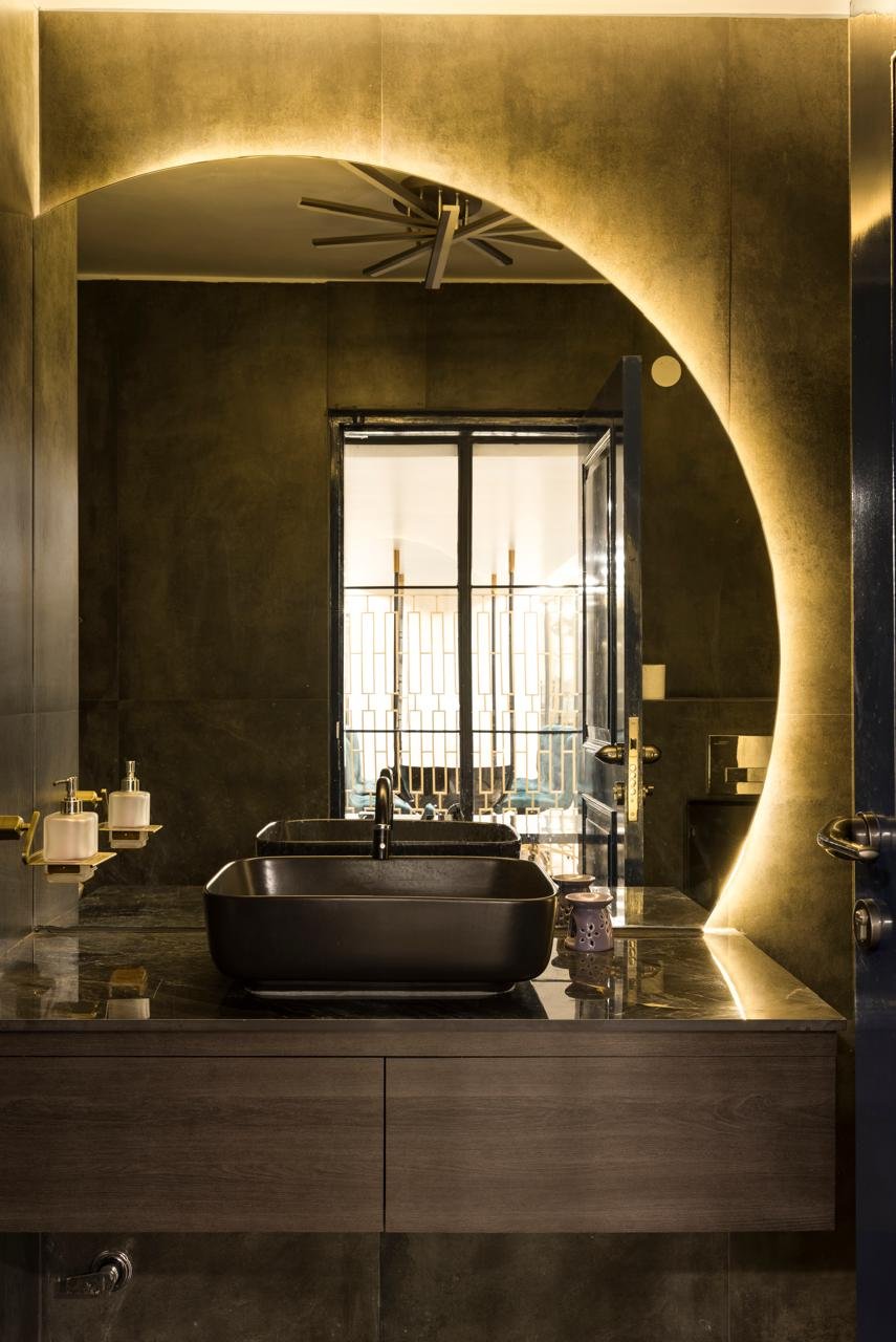 Dark stone bathroom with an illuminated arch and freestanding bathtub