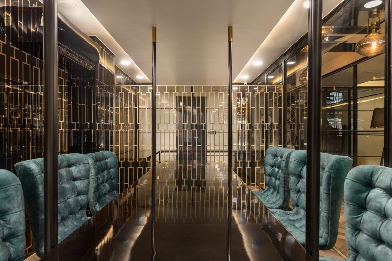 Office passage with mirrored partitions and teal seating