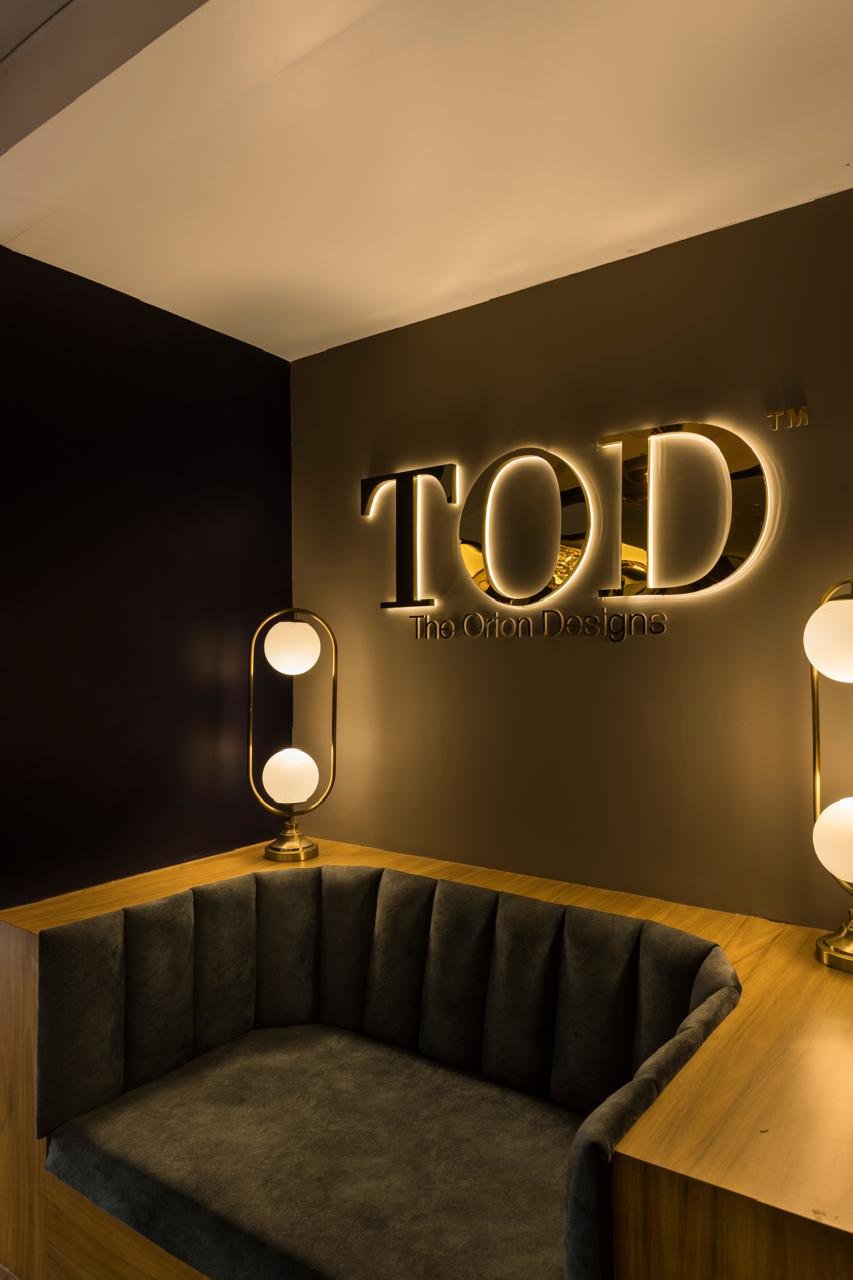 Illuminated TOD The Orion Designs sign above lounge seating