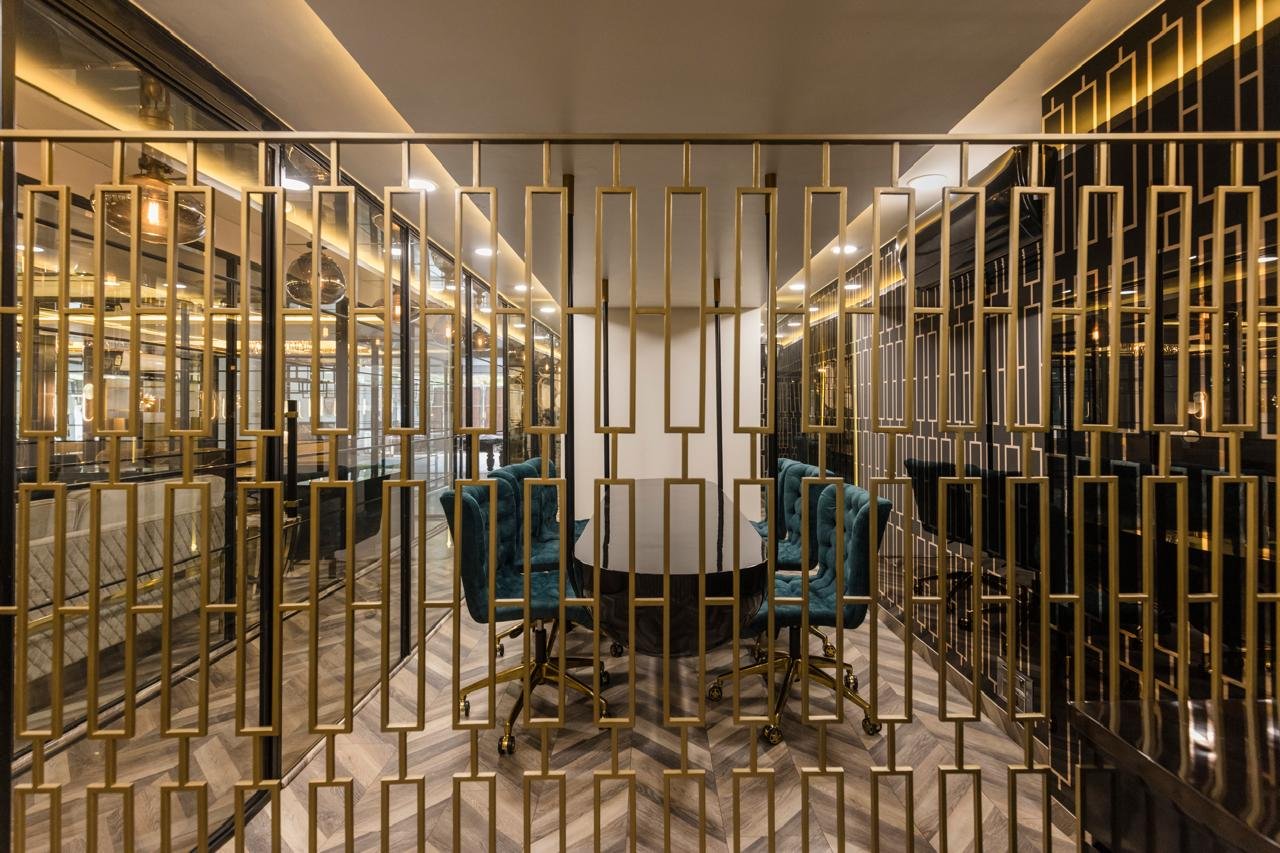 Teal meeting chairs seen through a decorative gold partition